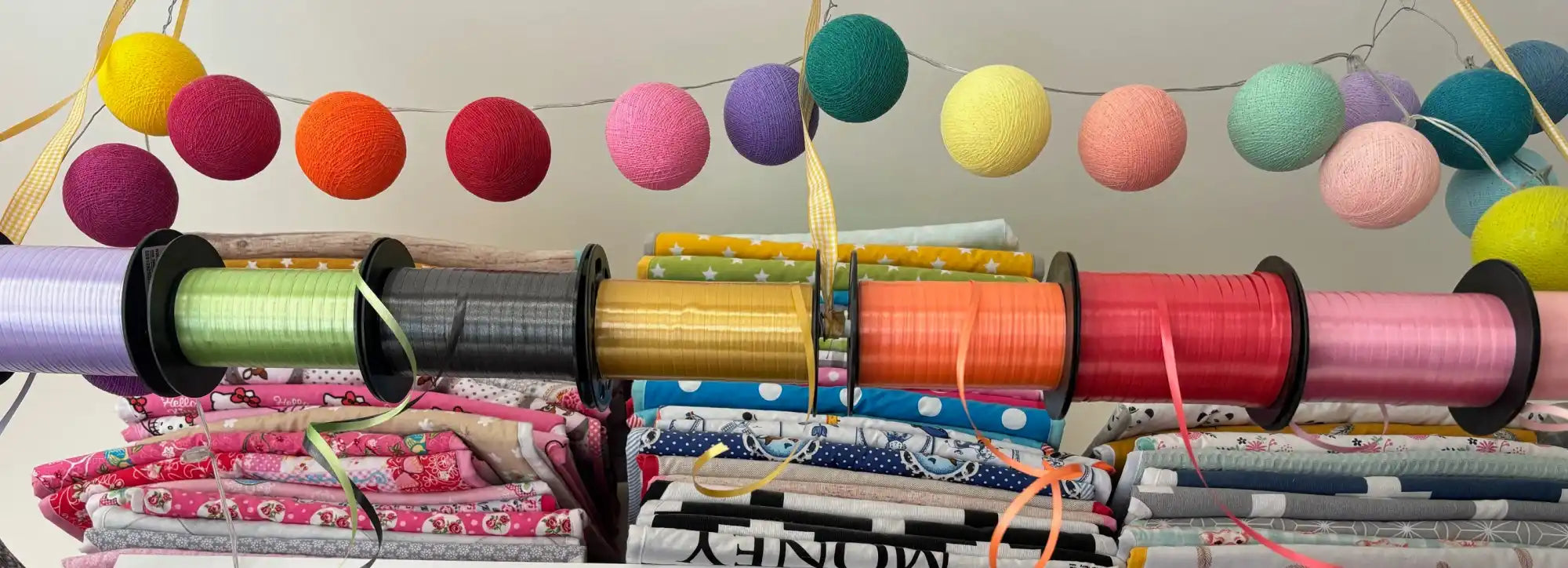 Een kleurrijk tafereel van lintrollen en stoffenklaarzen, met decoratieve bolletjes garen gespannen bovenop.