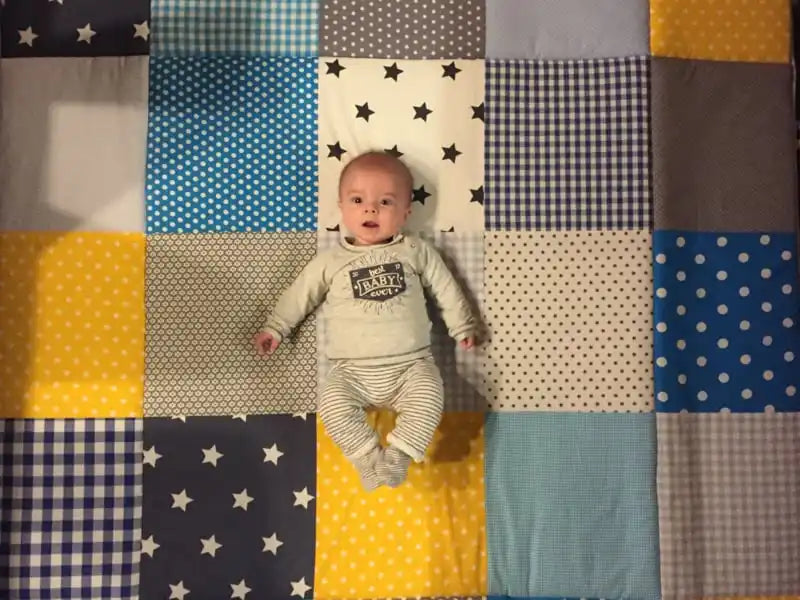 Een baby die een lichtgekleurde langemouwen shirt en gestreepte broek draagt.